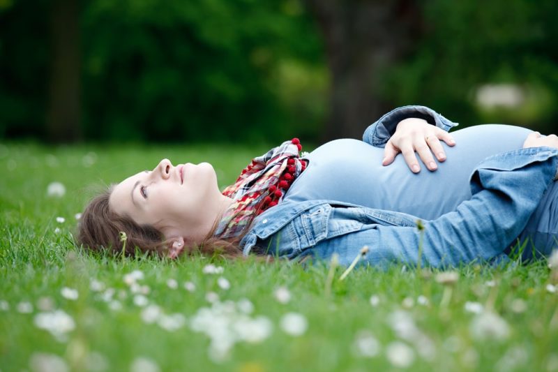 modernmamahypnobirthing pregnant woman lying in the grass
