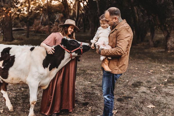 photo of pregnant Corrin together with her husband, daughter and a cow